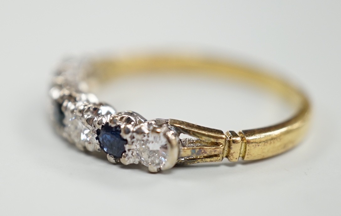 A modern 18ct gold, three stone sapphire and four stone diamond set half hoop ring, size P/Q, gross weight 2.9 grams.